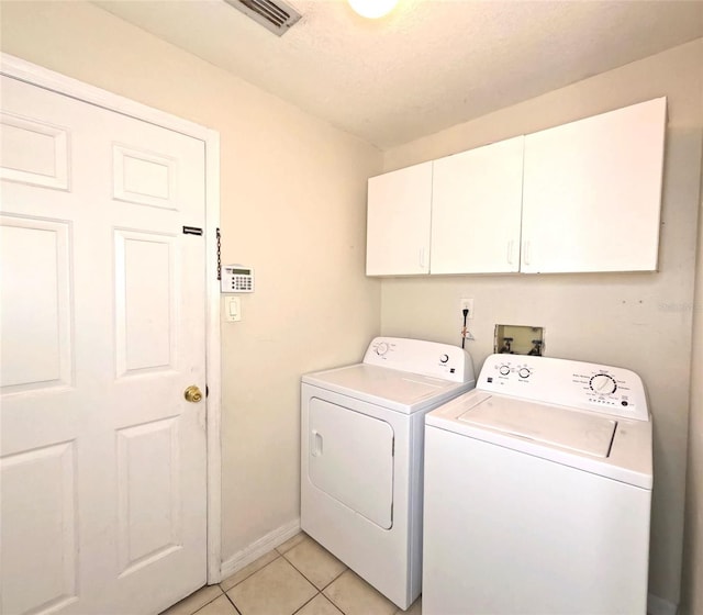 laundry room with cabinets, washing machine and clothes dryer, and light tile patterned flooring