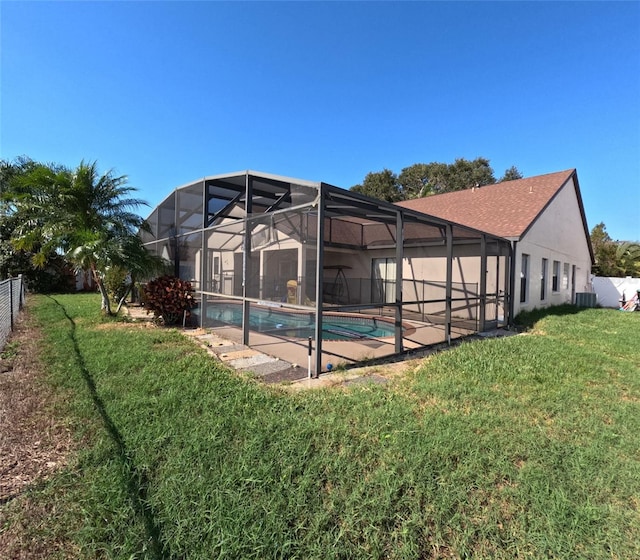 view of swimming pool with central air condition unit, glass enclosure, and a lawn