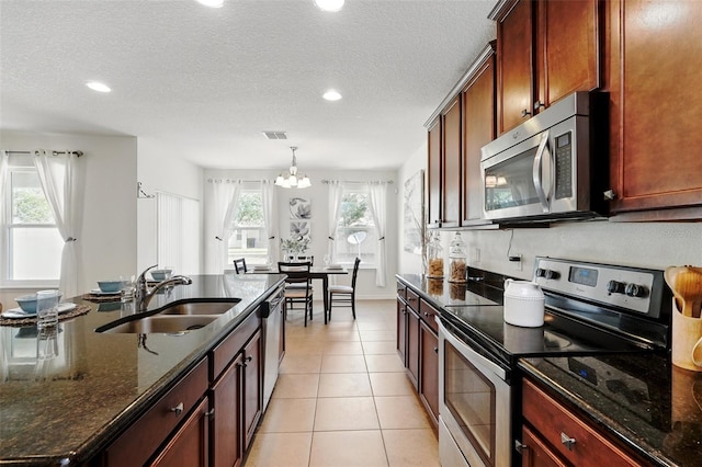 3270 Mt Vernon Way, Kissimmee, FL 34741 - kitchen featuring a sink, light tile patterned floors, a chandelier, dark stone counters, and stainless steel appliances