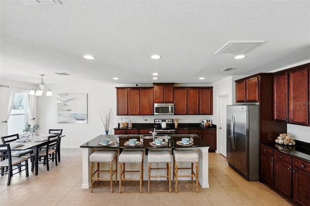 3270 Mt Vernon Way, Kissimmee, FL 34741 - kitchen featuring visible vents, a breakfast bar, dark countertops, and stainless steel appliances