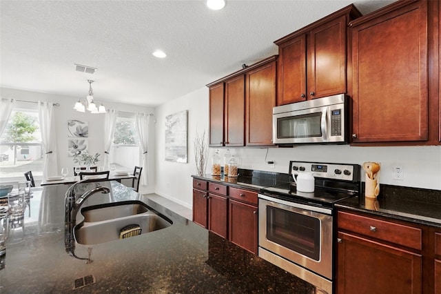 3270 Mt Vernon Way, Kissimmee, FL 34741 - kitchen with dark stone countertops, a sink, a notable chandelier, visible vents, and appliances with stainless steel finishes