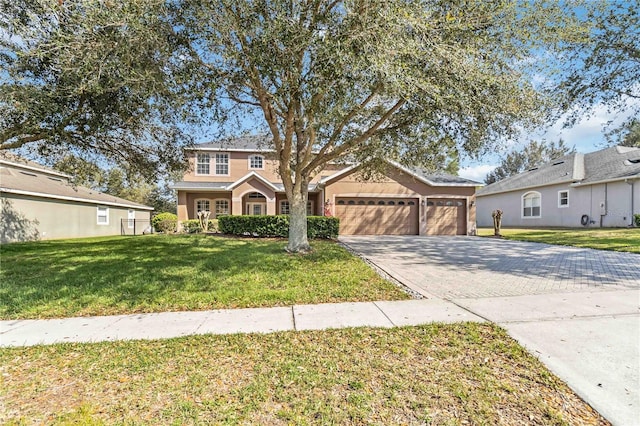 view of front of house with an attached garage, stucco siding, aphalt driveway, and a front yard