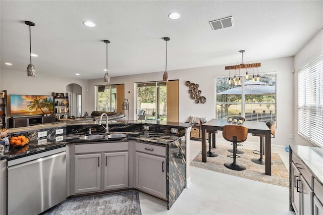 kitchen with arched walkways, gray cabinetry, open floor plan, dishwasher, and pendant lighting