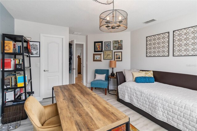 bedroom featuring light wood-style floors, a chandelier, visible vents, and baseboards