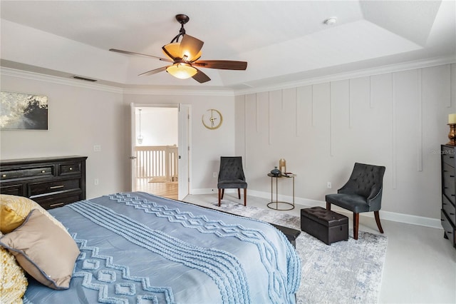 bedroom with a tray ceiling, crown molding, visible vents, ceiling fan, and baseboards