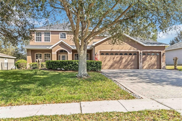 view of front of house featuring a garage, a front yard, decorative driveway, and stucco siding