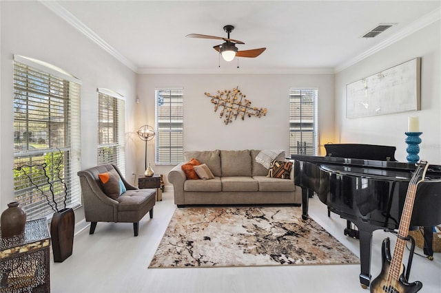 living room featuring visible vents, ornamental molding, ceiling fan, and a wealth of natural light