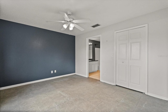 unfurnished bedroom featuring baseboards, visible vents, tile patterned flooring, a closet, and connected bathroom