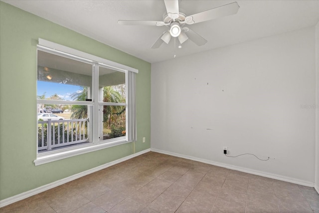 tiled spare room featuring baseboards and ceiling fan