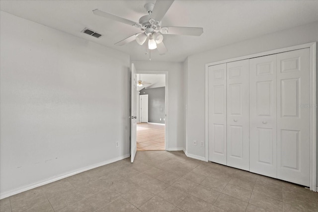 unfurnished bedroom featuring light tile patterned flooring, baseboards, visible vents, a closet, and ceiling fan