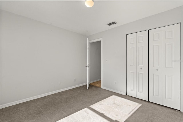 unfurnished bedroom with baseboards, visible vents, tile patterned flooring, and a closet
