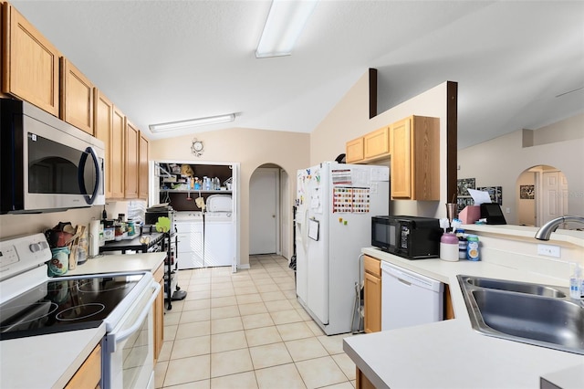 kitchen featuring sink, white appliances, light tile patterned floors, independent washer and dryer, and vaulted ceiling