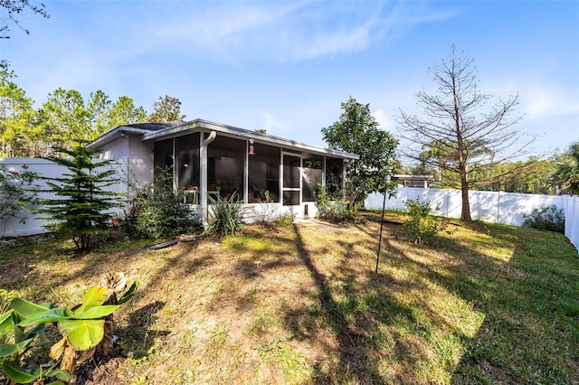 back of house with a sunroom and a lawn