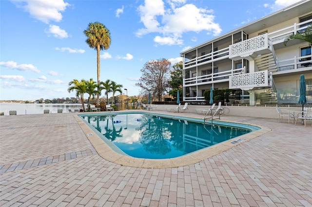 view of swimming pool featuring a patio and a water view