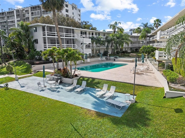 view of swimming pool with grilling area, a patio, and a lawn