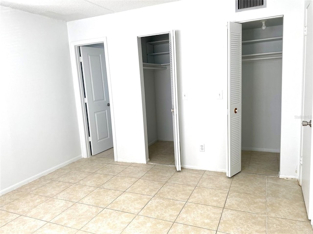 unfurnished bedroom with multiple closets, a spacious closet, and light tile patterned floors