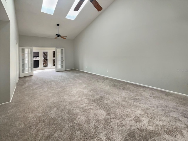 unfurnished living room with high vaulted ceiling, a skylight, carpet flooring, ceiling fan, and french doors