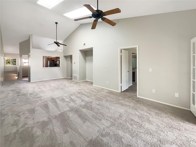 unfurnished living room featuring ceiling fan, carpet floors, high vaulted ceiling, and a skylight