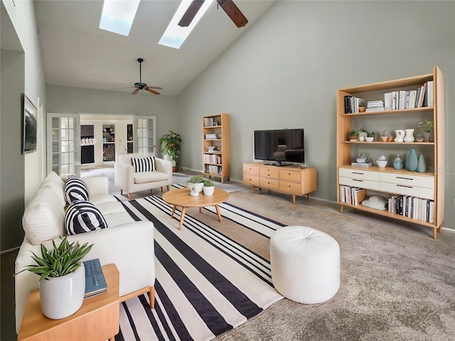 living room featuring high vaulted ceiling, carpet floors, ceiling fan, and a skylight