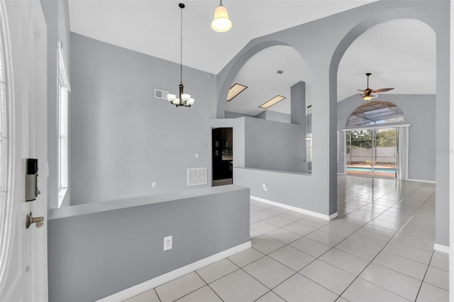 unfurnished room with ceiling fan with notable chandelier, vaulted ceiling, and light tile patterned flooring