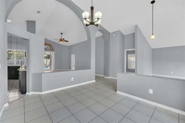 unfurnished living room featuring lofted ceiling, ceiling fan with notable chandelier, and tile patterned floors