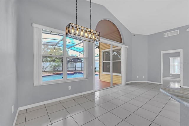 unfurnished dining area with lofted ceiling, light tile patterned floors, a chandelier, and a healthy amount of sunlight