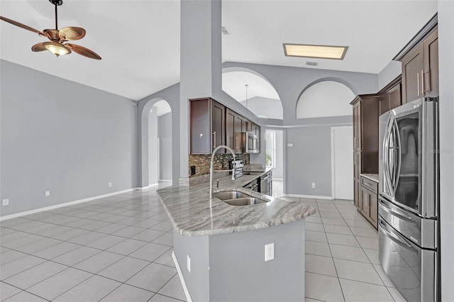 kitchen with light tile patterned floors, backsplash, vaulted ceiling, and stainless steel appliances