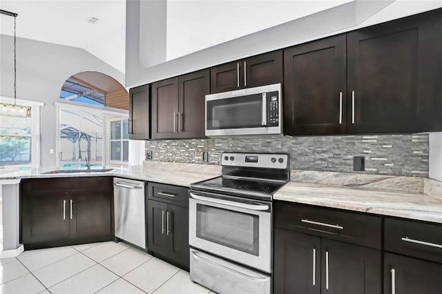 kitchen featuring vaulted ceiling, appliances with stainless steel finishes, tasteful backsplash, sink, and hanging light fixtures