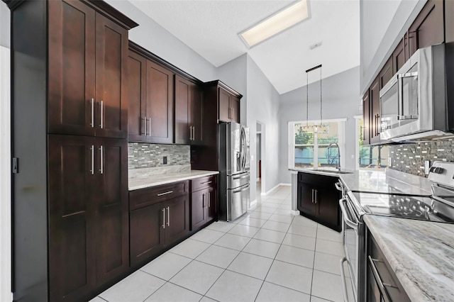 kitchen with lofted ceiling, sink, light tile patterned floors, appliances with stainless steel finishes, and hanging light fixtures