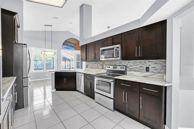 kitchen with pendant lighting, sink, stainless steel appliances, light stone counters, and decorative backsplash