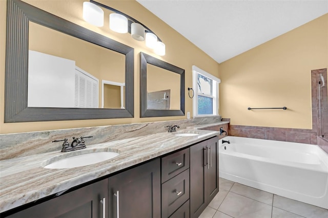 bathroom featuring lofted ceiling, tile patterned floors, a bathtub, and vanity