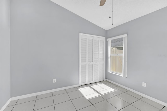 empty room featuring ceiling fan, lofted ceiling, and light tile patterned floors