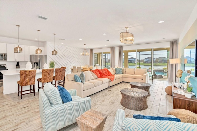 living room with an inviting chandelier, light hardwood / wood-style flooring, and a water view