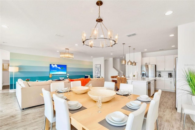 dining room with a chandelier, sink, and light hardwood / wood-style flooring