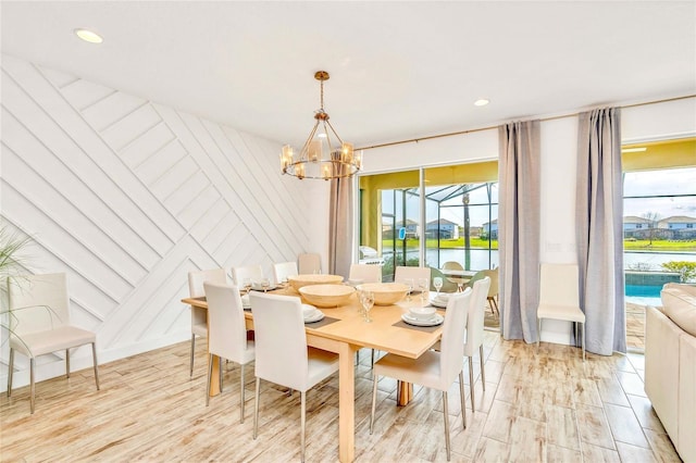 dining space featuring a water view, an inviting chandelier, and light wood-type flooring