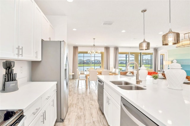 kitchen with stainless steel dishwasher, decorative light fixtures, sink, and white cabinets