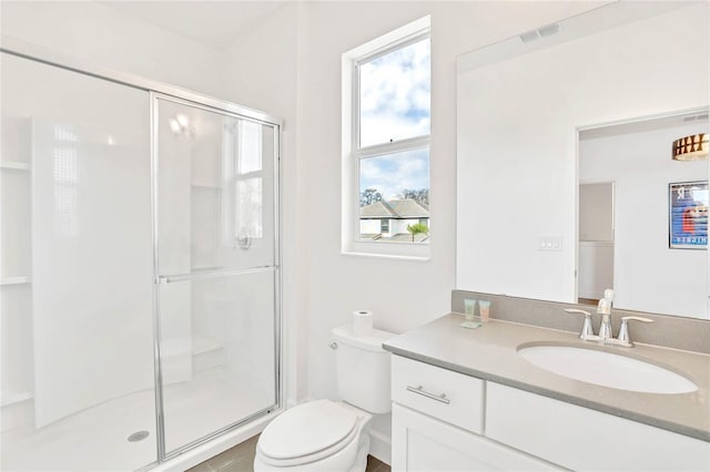 bathroom featuring vanity, a shower with door, and toilet