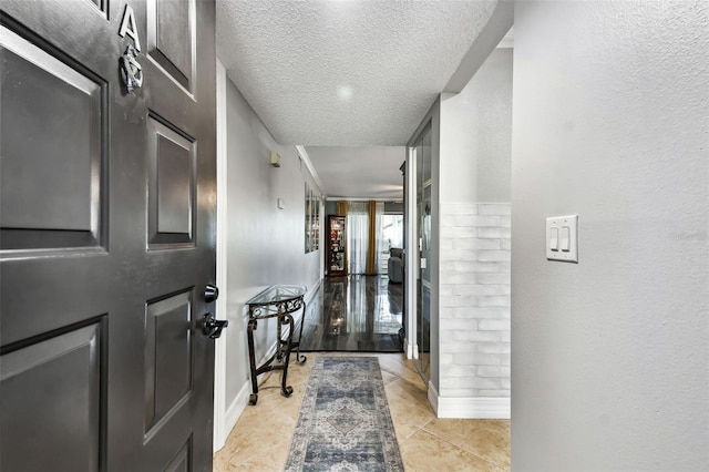 corridor with a textured ceiling and light tile patterned flooring