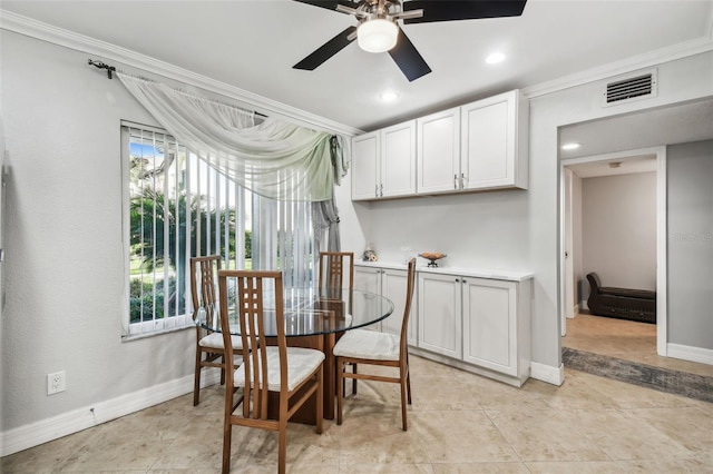 tiled dining space with ceiling fan and ornamental molding