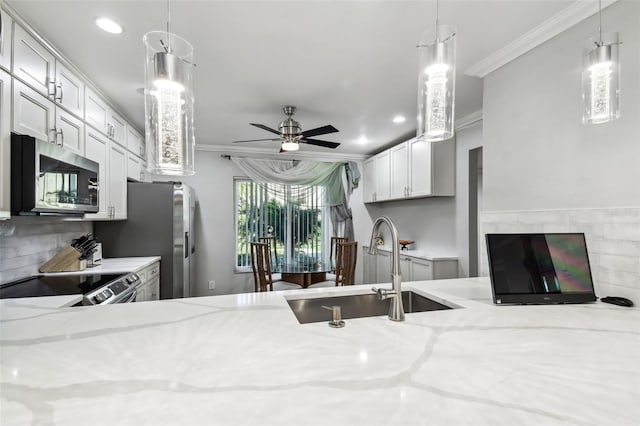 kitchen with sink, light stone counters, crown molding, decorative light fixtures, and appliances with stainless steel finishes