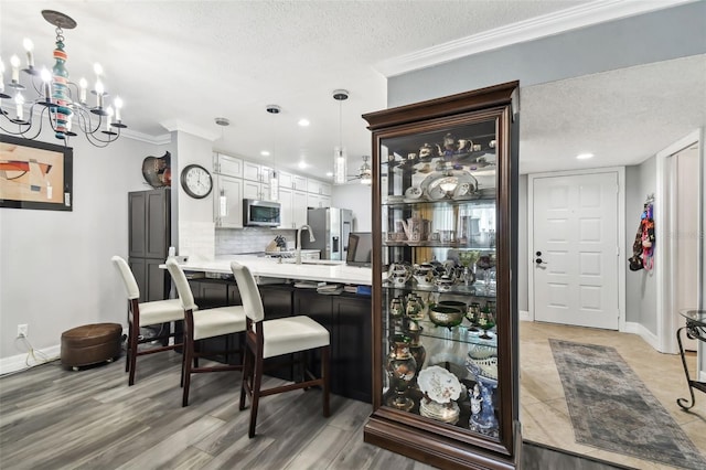 interior space with white cabinetry, appliances with stainless steel finishes, pendant lighting, and crown molding