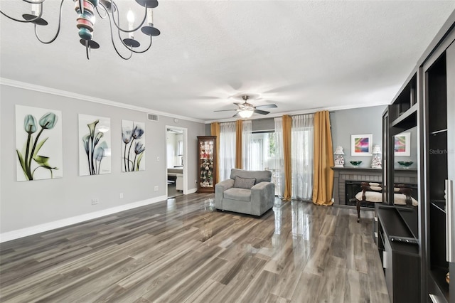 living room with hardwood / wood-style flooring, ornamental molding, a brick fireplace, and a textured ceiling