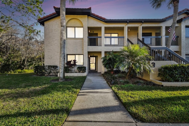 view of front of home with a balcony and a lawn