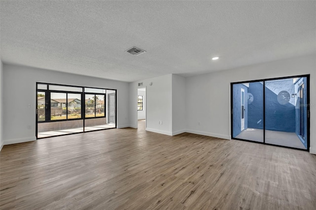 spare room featuring light hardwood / wood-style floors and a textured ceiling