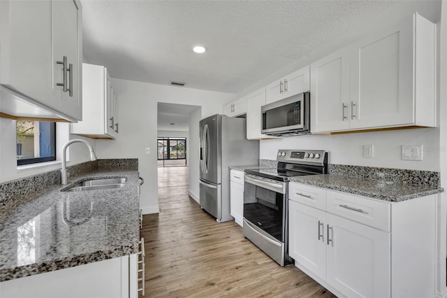 kitchen with dark stone countertops, sink, white cabinets, and appliances with stainless steel finishes