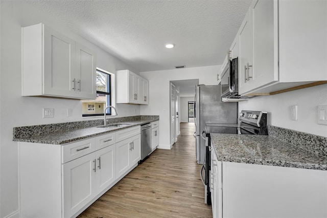 kitchen featuring appliances with stainless steel finishes, sink, white cabinets, and light stone counters