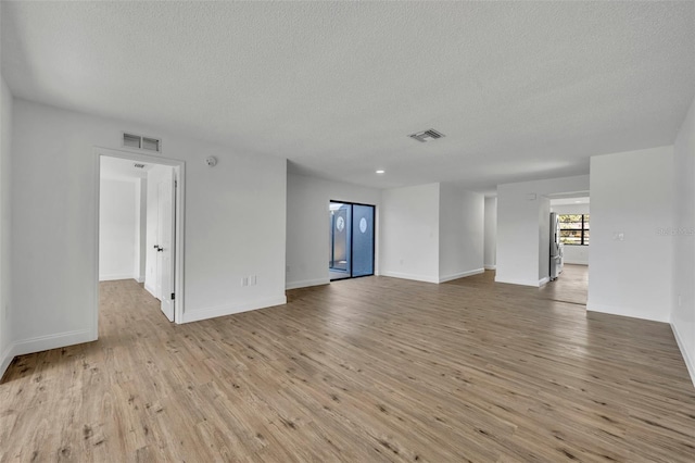 unfurnished room with a textured ceiling and light hardwood / wood-style floors