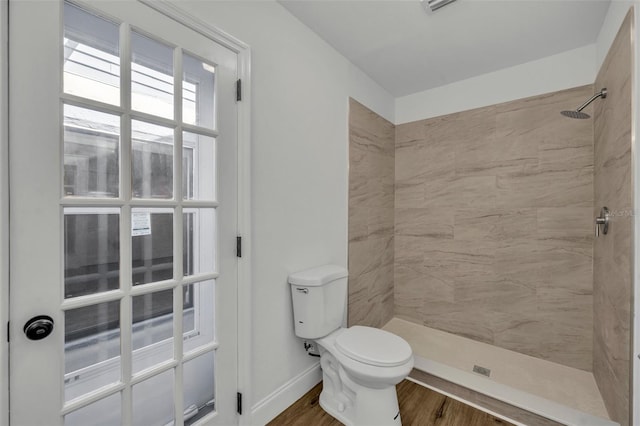 bathroom with tiled shower, hardwood / wood-style floors, and toilet