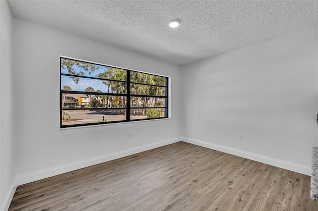 spare room with a textured ceiling and light hardwood / wood-style floors