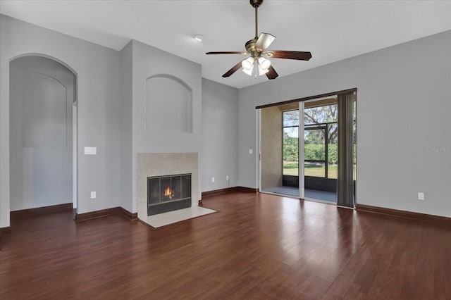 unfurnished living room featuring dark wood-type flooring, a tile fireplace, and ceiling fan